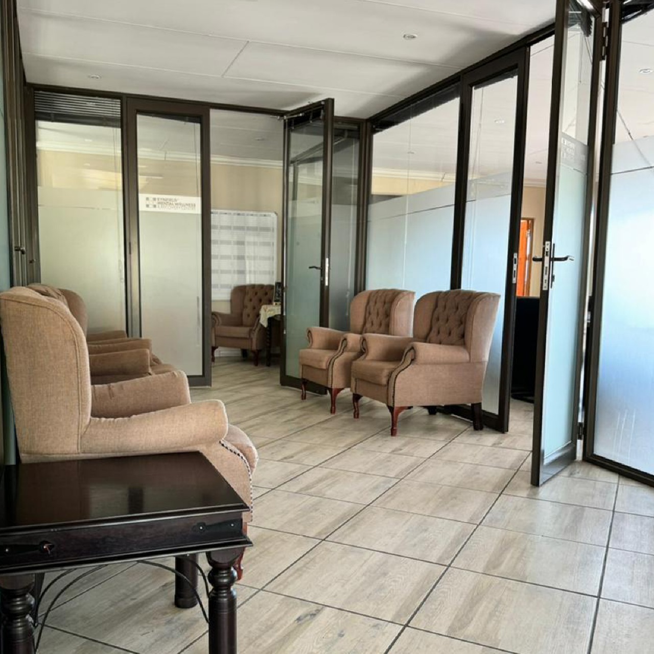 Waiting area upstairs at ARC Addiction Recovery Centre with plush armchairs, glass doors, and tiled flooring, located near the psychologists' rooms.